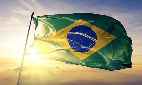 Brazilian flag - fabric waving over sunrise and misty sky.